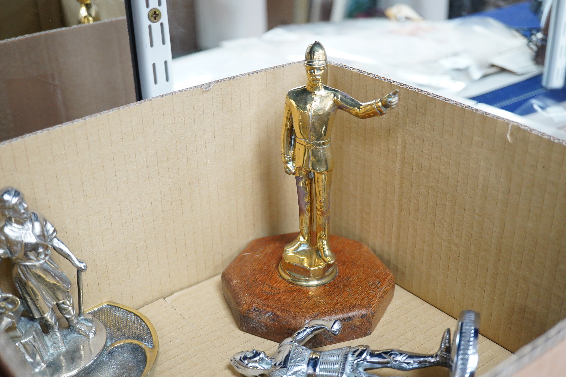 Five chrome and brass car mascots, including a knight, a policeman, a figure of Mercury, etc. together with two Art Deco table lighters as female figures, and an ashtray with the figure of a blacksmith (8)
